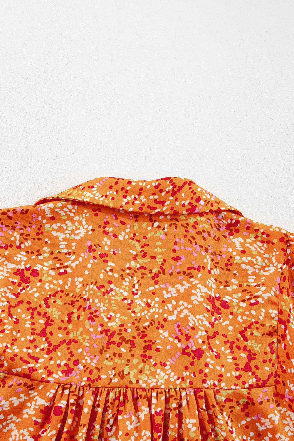 Orange abstract print babydoll blouse, back view showing collar and fabric detail.