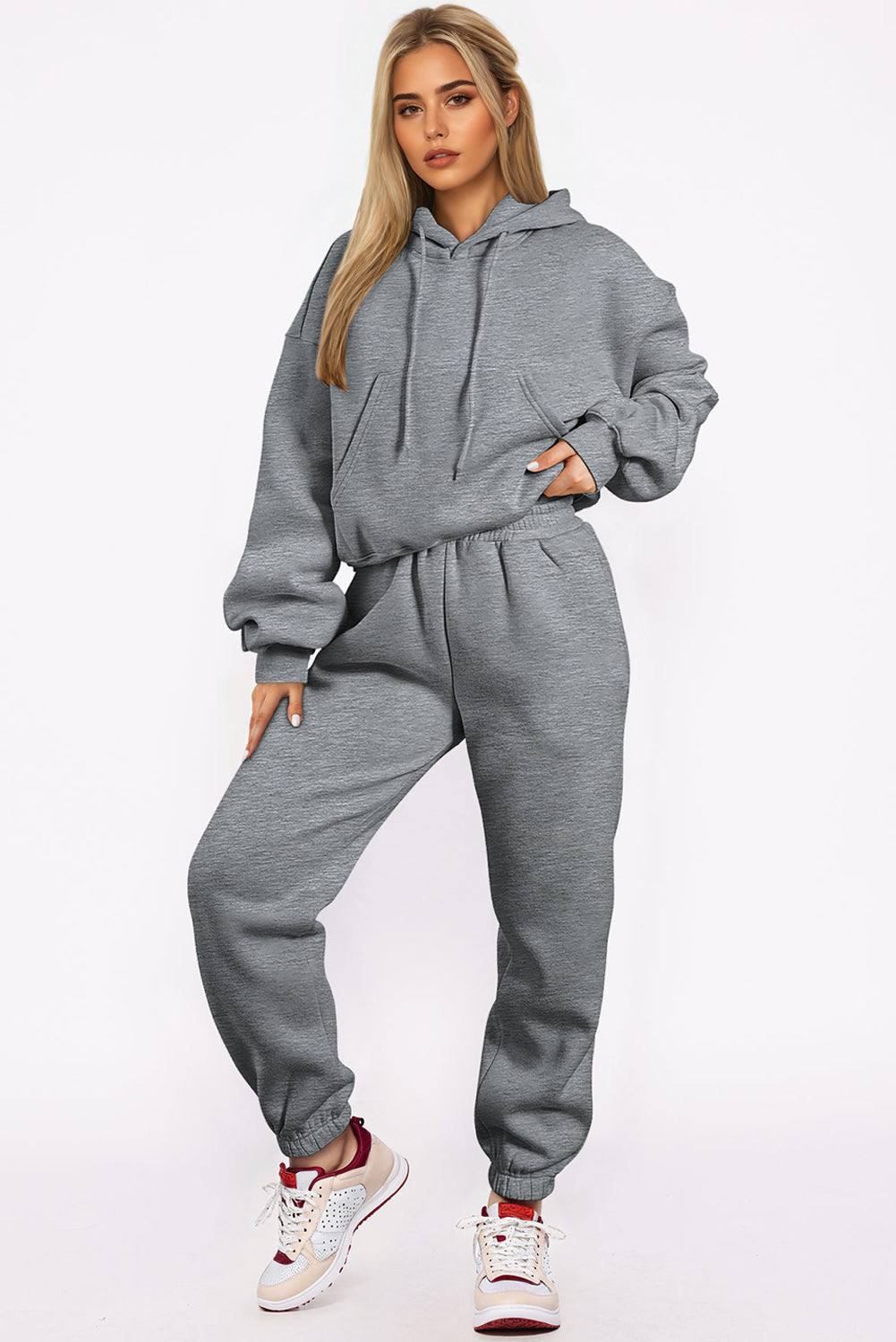 Woman wearing gray solid drop shoulder hoodie and joggers activewear set with sneakers