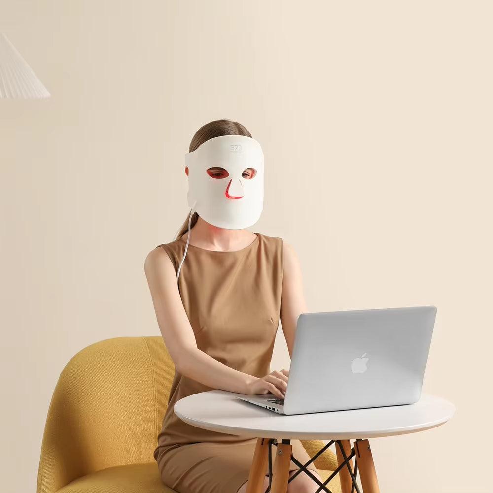 18‑in‑1 373™ Gold Collagen LED Mask women relaxing wearing the mask