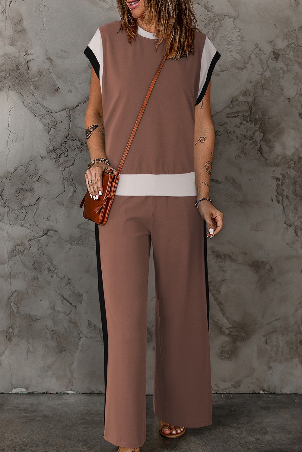 Woman wearing chestnut color block casual two-piece outfit with neutral tones against gray textured wall background