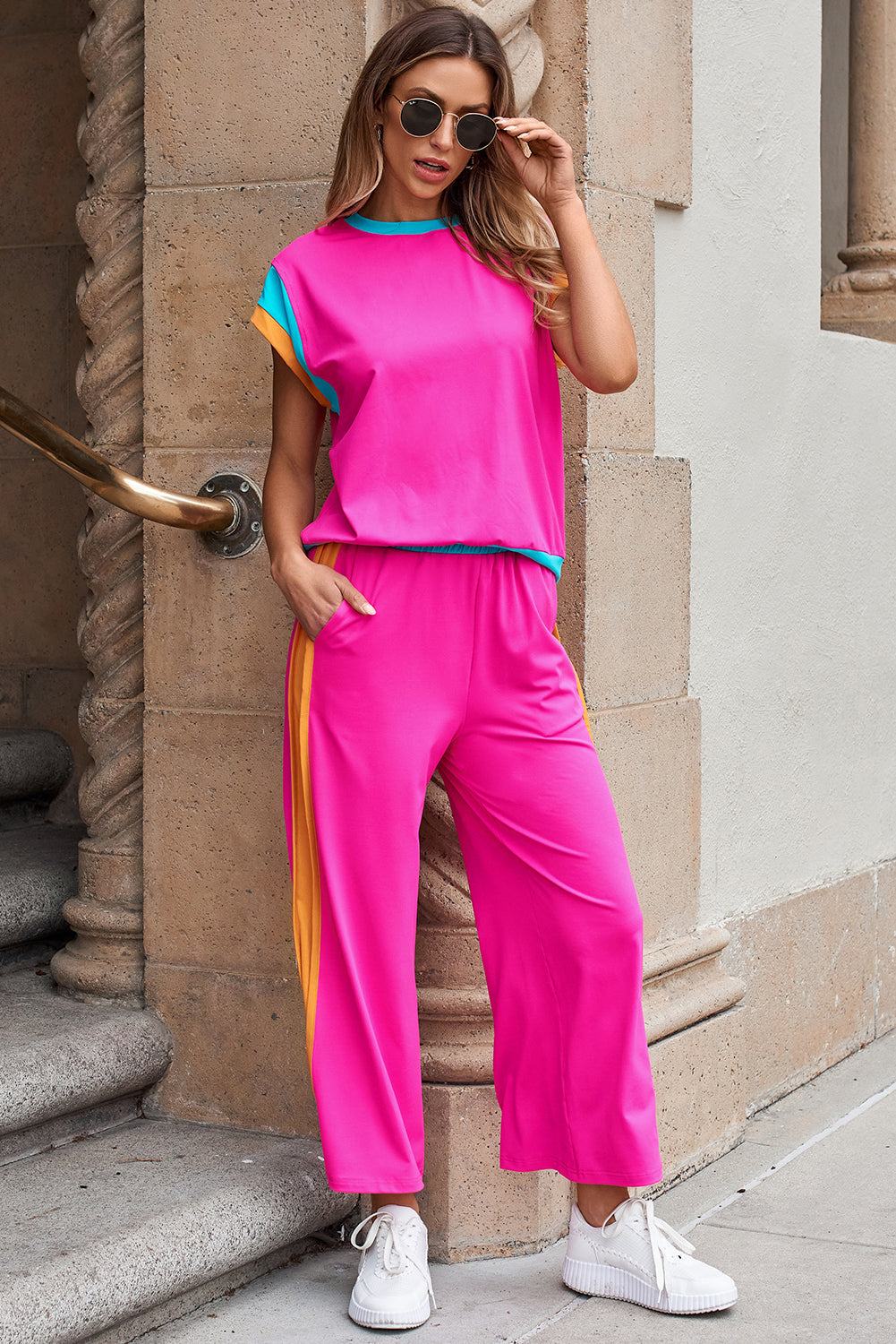 Woman wearing strawberry pink color block casual two-piece set with relaxed fit top and jogger pants, styled with white sneakers and sunglasses.