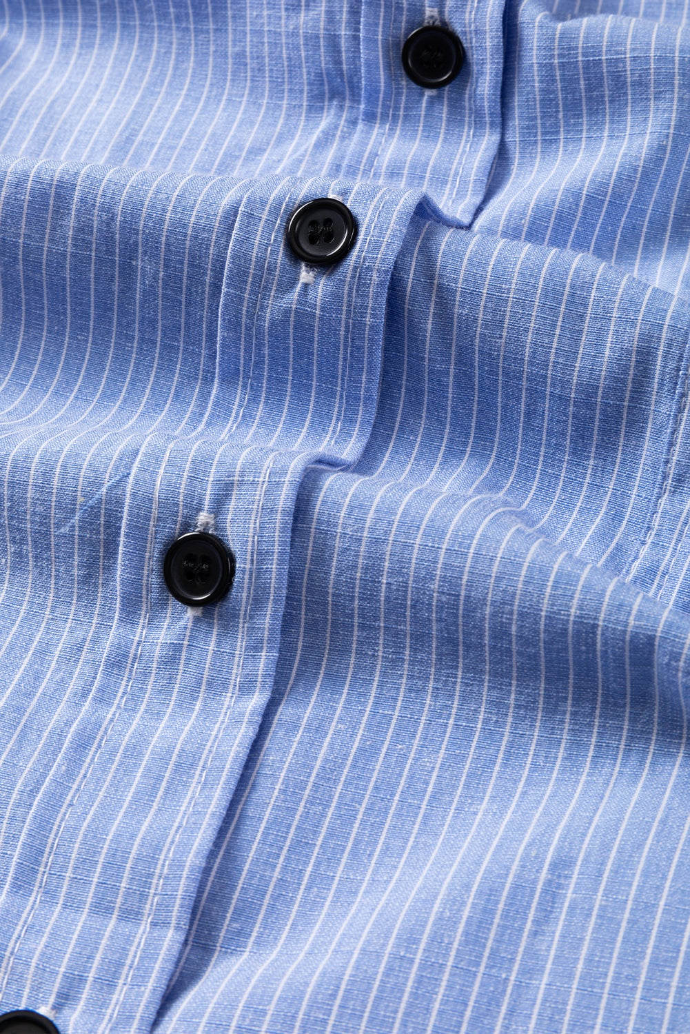 Sky blue striped long shirt with black buttons and roll-tab sleeves detail close-up