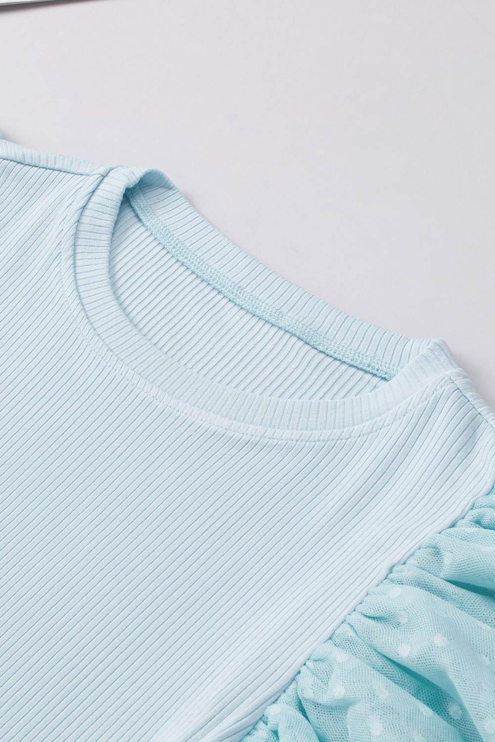 Close-up of feminine cap sleeve top collar showing gathered neckline and fine fabric texture