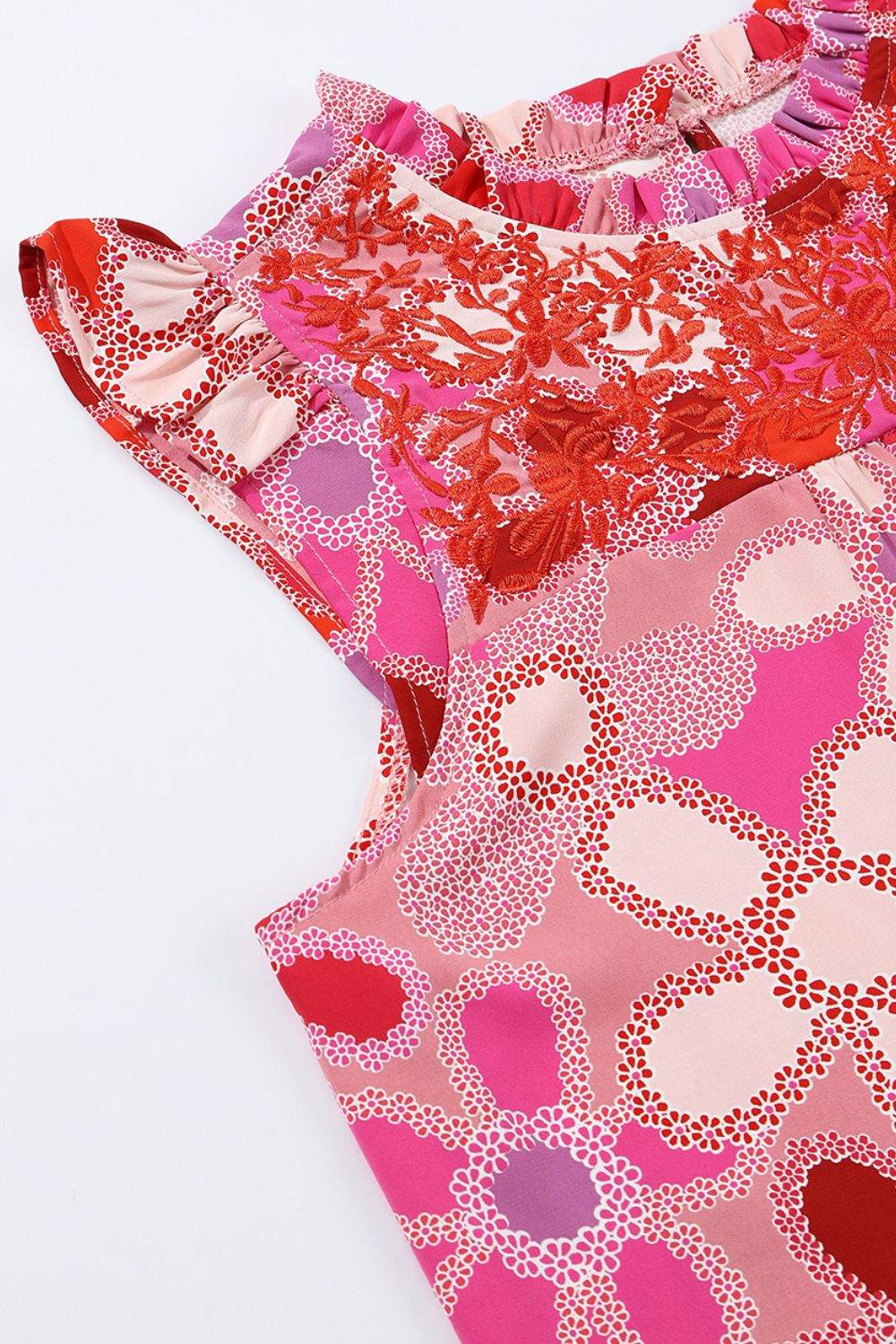 Floral ruffled cap sleeve blouse with embroidered detail and pink-red floral pattern.