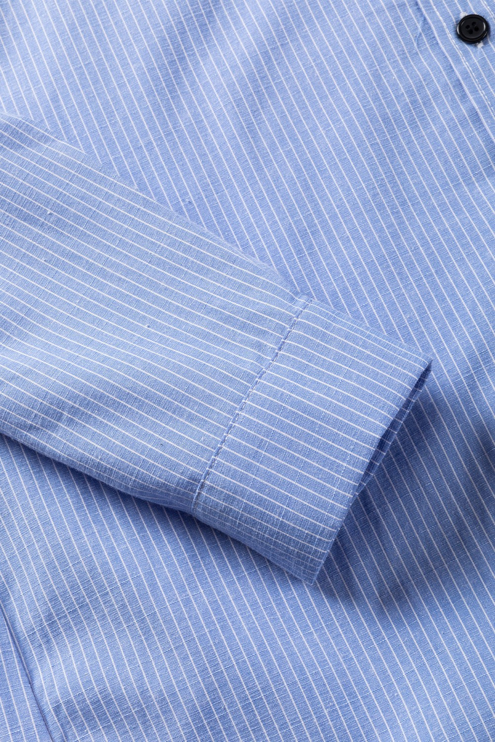 Sky blue long shirt with white stripes, roll-tab sleeve, and chest pocket close-up.