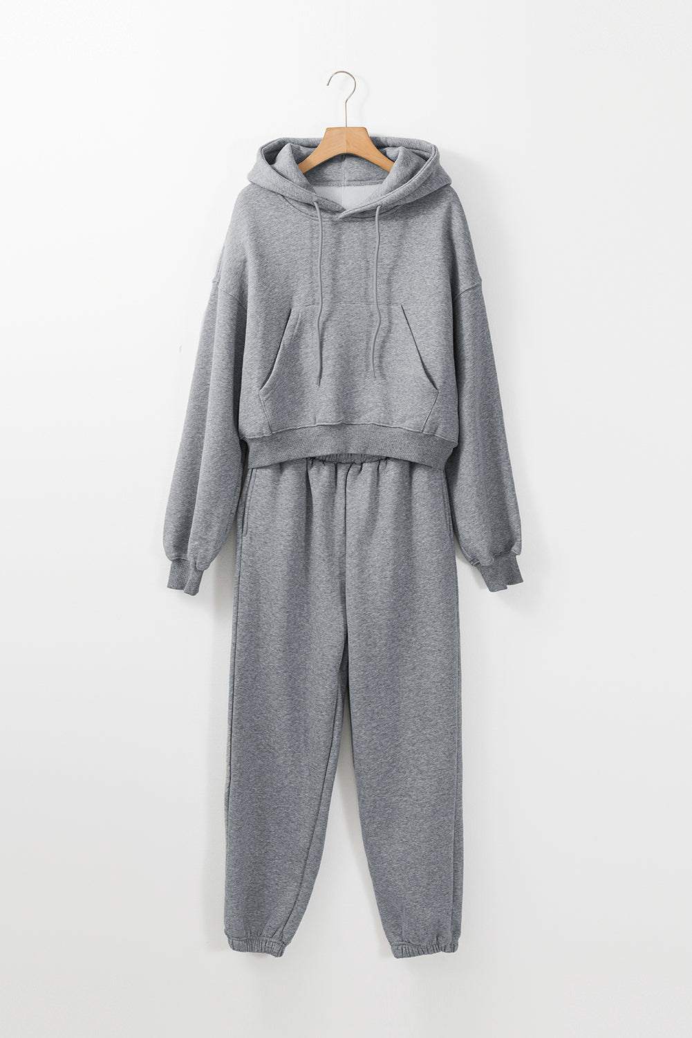 Gray solid drop shoulder hoodie and joggers activewear set hanging on wooden hanger against white background