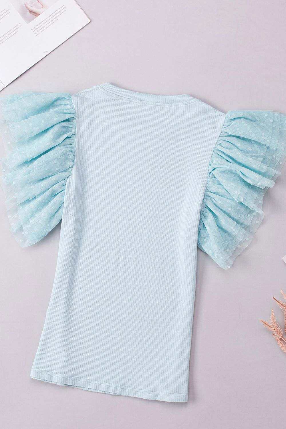 Back of soft pastel top with subtle ruffle accents and smooth finish for everyday wear