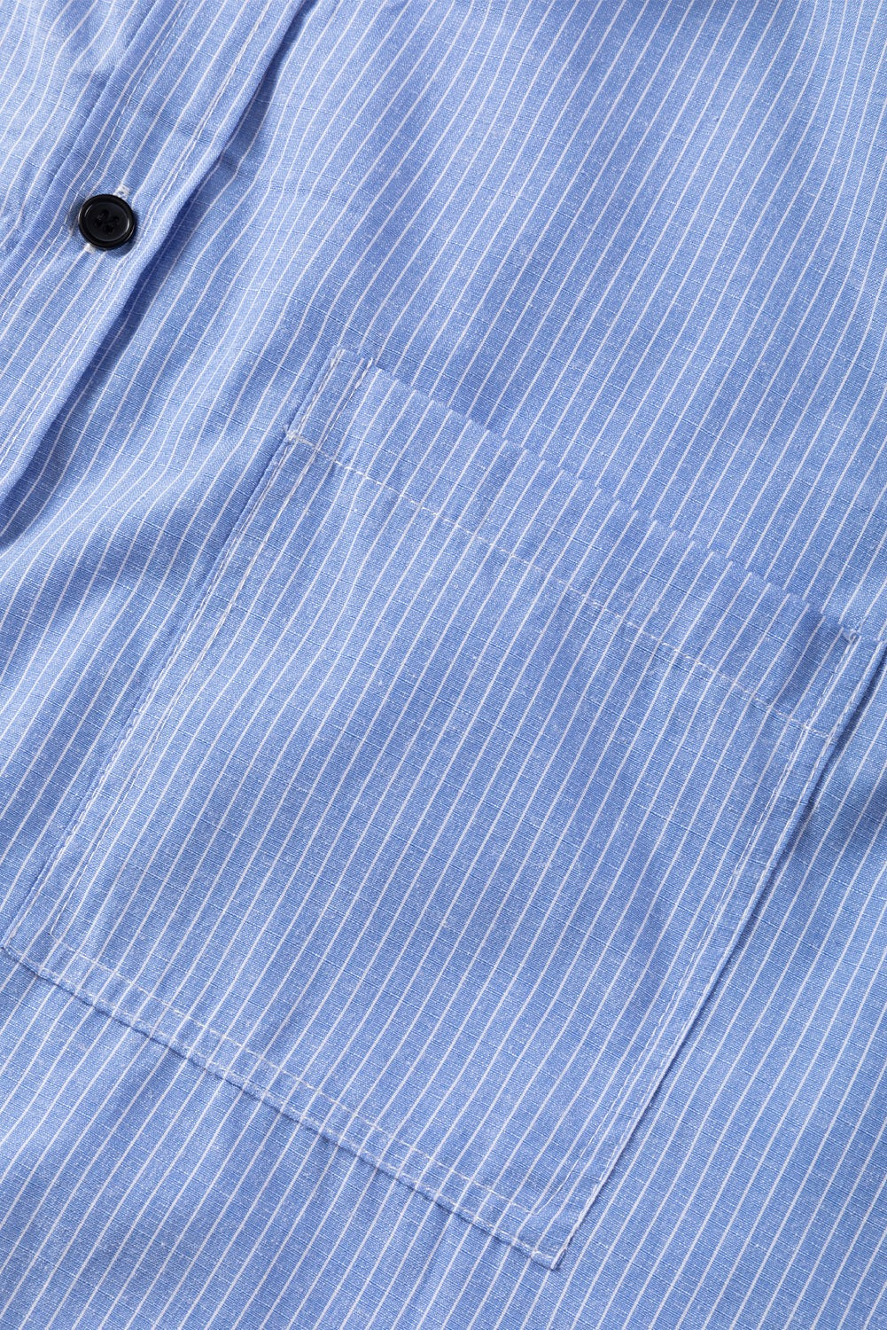 Close-up of sky blue striped long shirt with roll-tab sleeves and a chest pocket detail