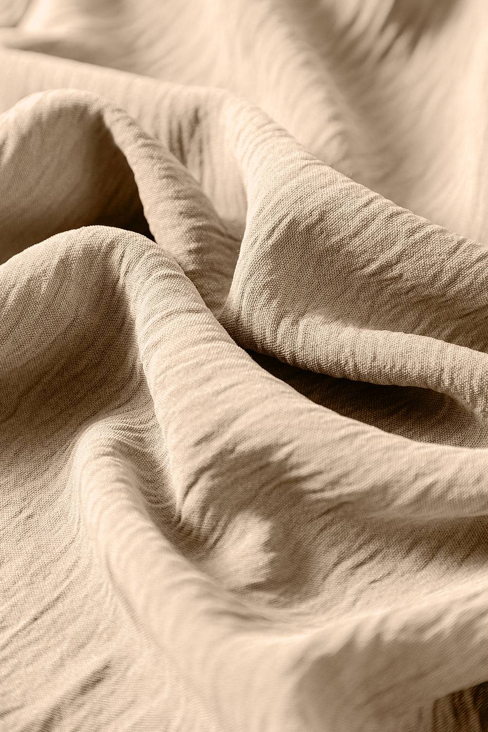 Close-up of apricot fabric texture for spaghetti straps wide leg jumpsuit with waist tie and pockets