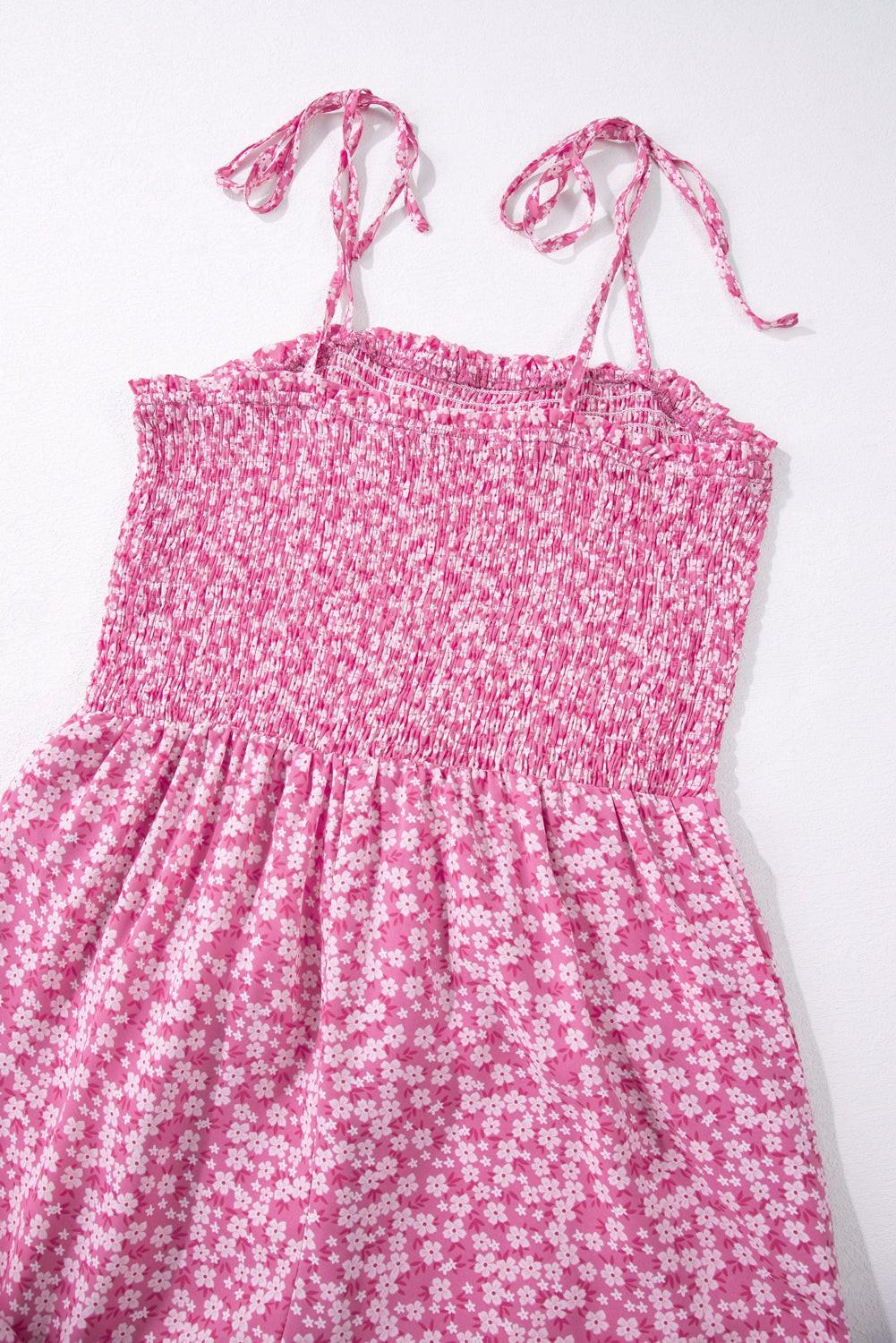 Pink floral Phalaenopsis jumpsuit with smocked bodice, thin adjustable straps, and wide-leg design.