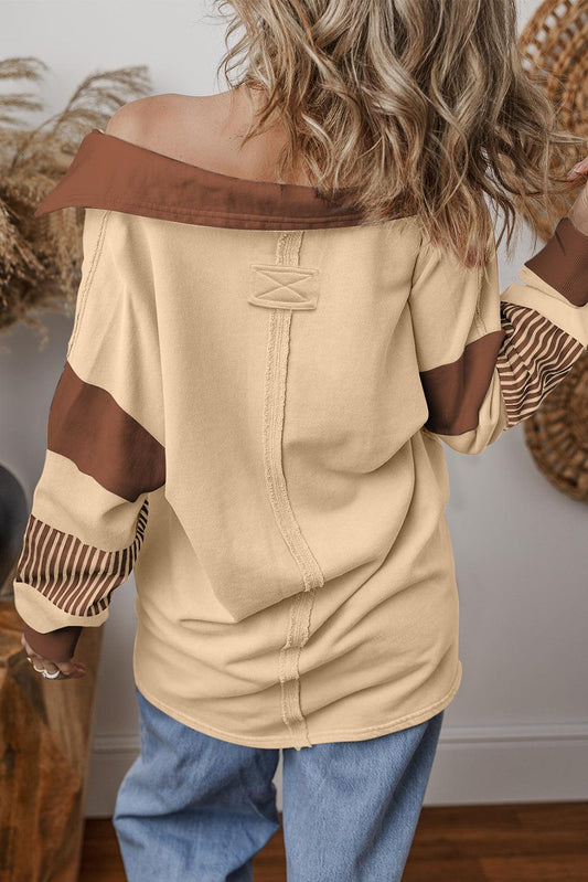 Back view of a light French beige colorblock sweatshirt with brown stripes and contrast collar worn with blue jeans, featuring patchwork pullover design and relaxed fit.
