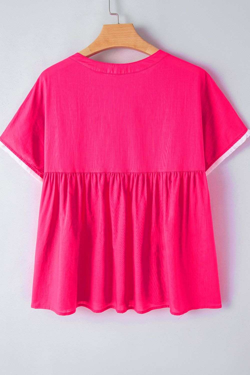 Bright pink summer blouse with embroidered tassel tie and geometric neck design, highlighting a flowy, lightweight silhouette.