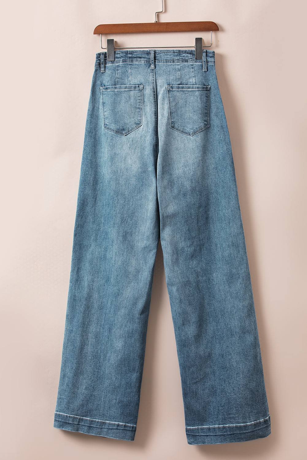 Dusk Blue medium wash straight loose leg jeans with unique multi-button design hanging on a wooden hanger.