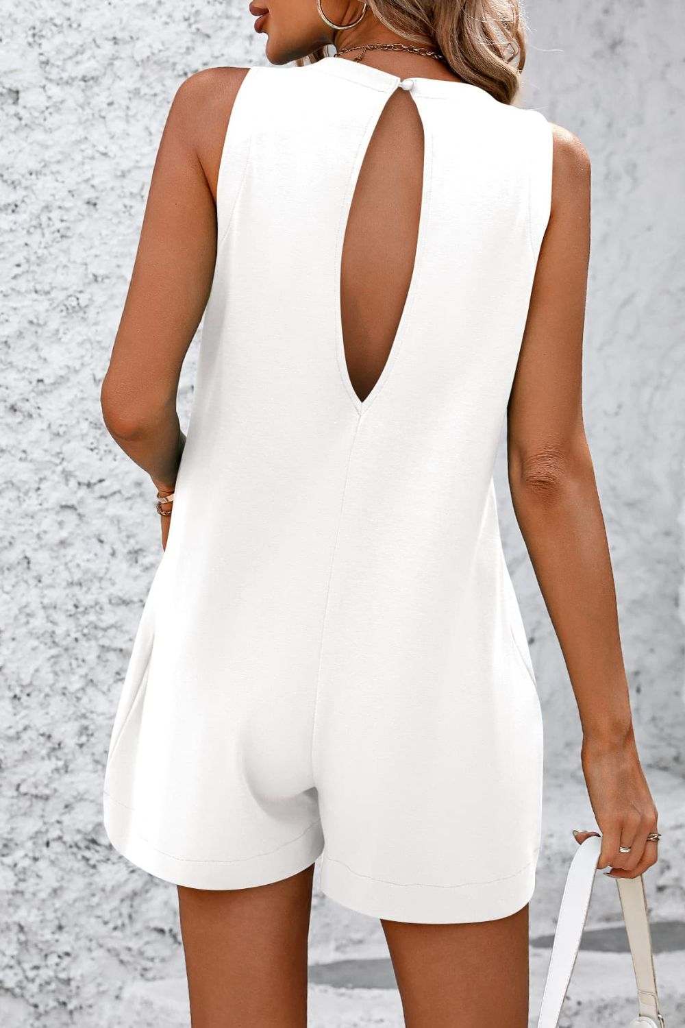 sleeveless romper with round neck and front pocket in white, back view
