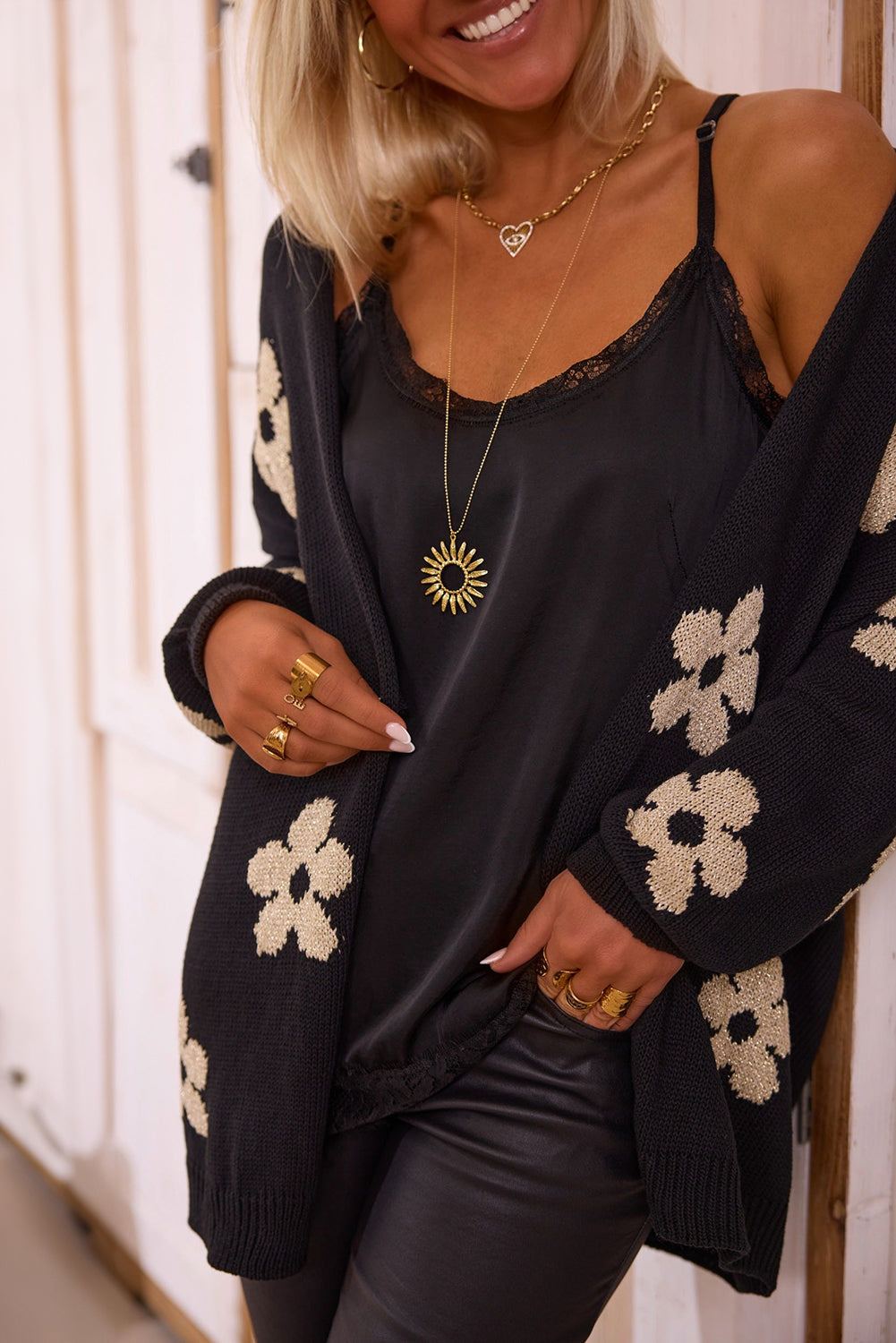 Black knitted open front cardigan with beige floral print, worn over a black camisole.