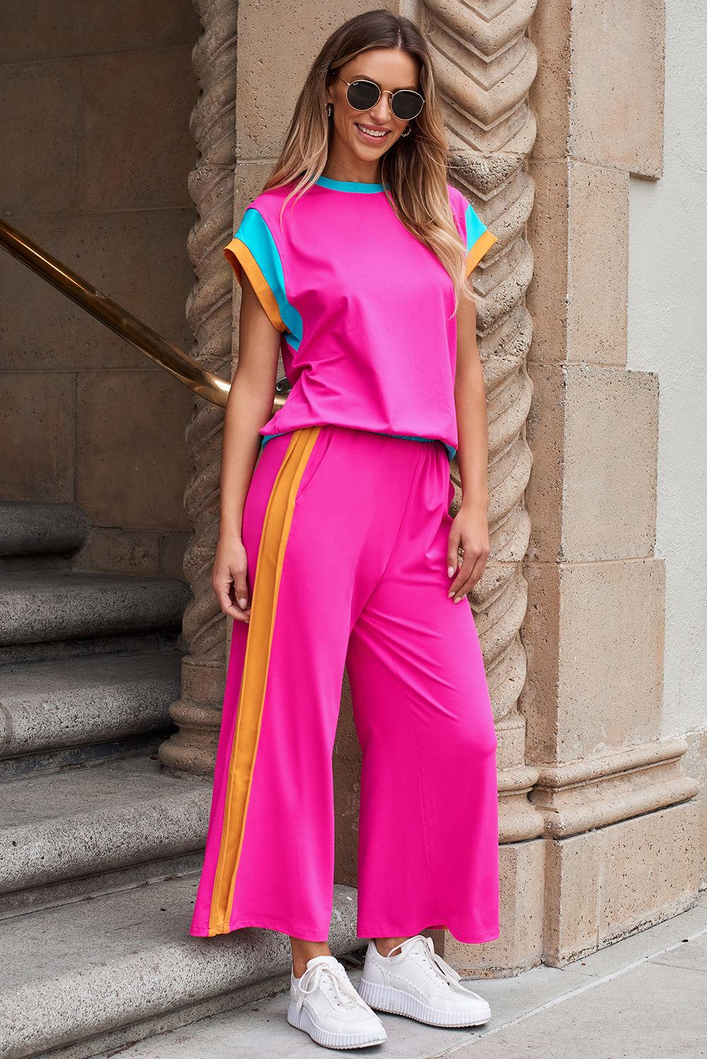 Woman wearing strawberry pink color block casual two-piece set with relaxed fit top and wide-leg joggers paired with white sneakers and sunglasses outdoors