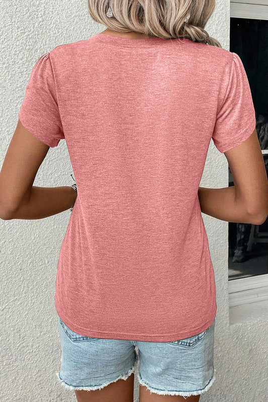 Back view of a woman wearing a rose tan petal sleeve V-neck t-shirt with short sleeves and light denim shorts