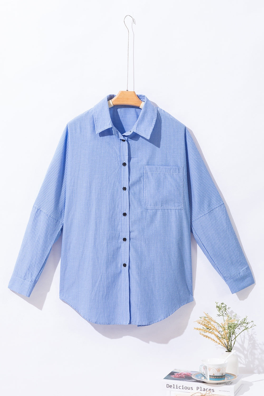 Sky blue striped long shirt with roll-tab sleeves and chest pocket on hanger