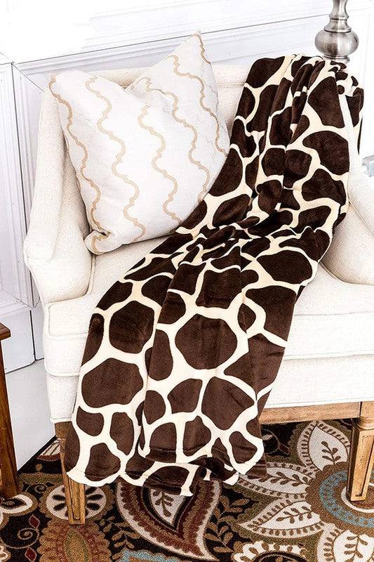 Giraffe print super soft cozy flannel blanket draped over chair.
