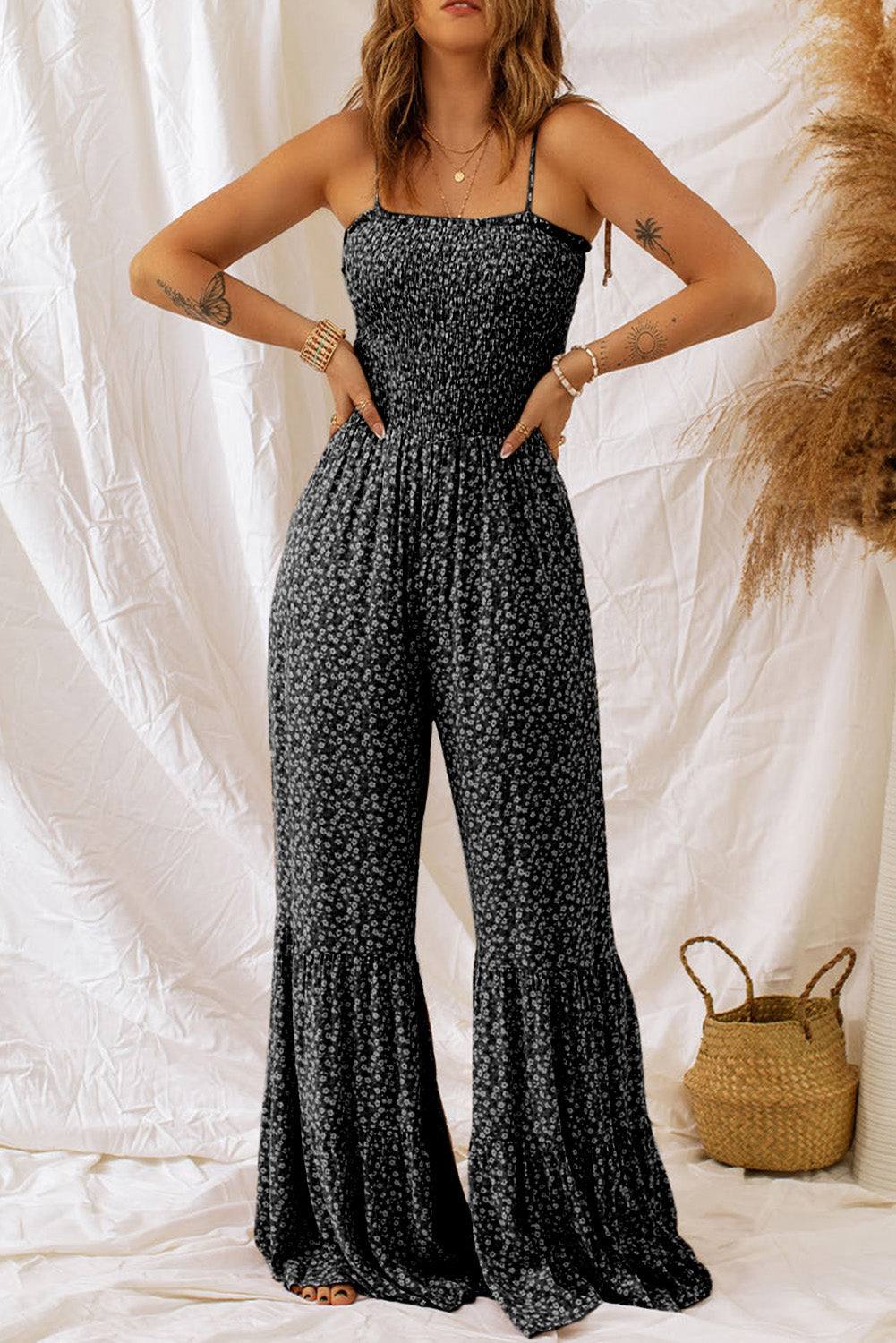 Black floral jumpsuit with thin straps, smocked bodice, and wide leg design.