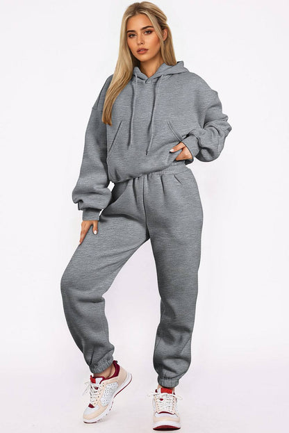 Woman wearing gray solid drop shoulder hoodie and joggers activewear set with sneakers