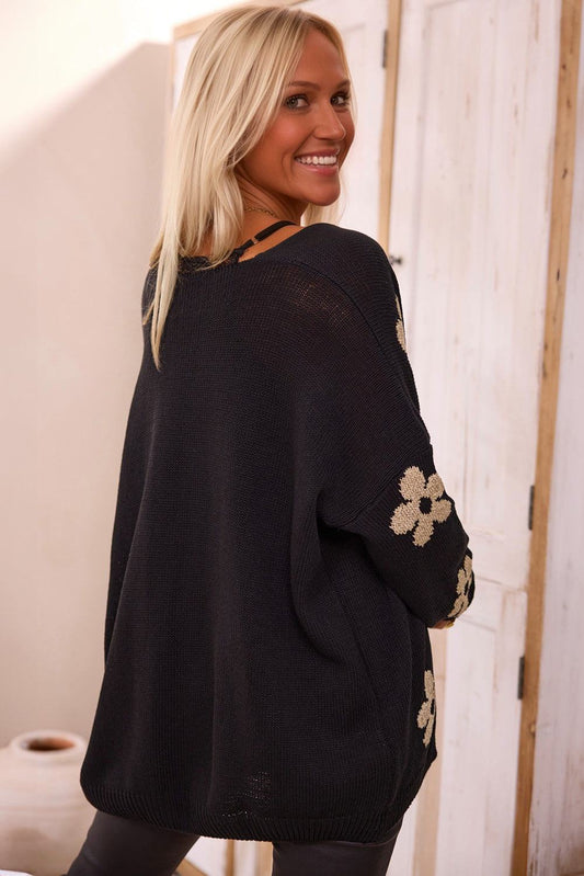 Woman wearing black floral print knitted open front loose cardigan indoors