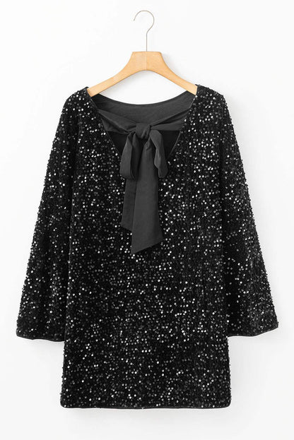Black sequin mini dress with long sleeves and knot cutout back on hanger.