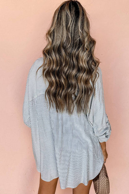 Woman wearing DEAR-LOVER striped roll-tab sleeve pocketed long shirt viewed from back against peach background