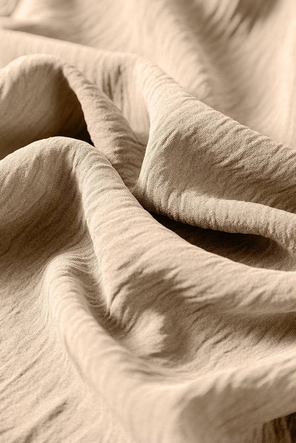 Close-up of apricot fabric texture for spaghetti straps wide leg jumpsuit with waist tie and pockets