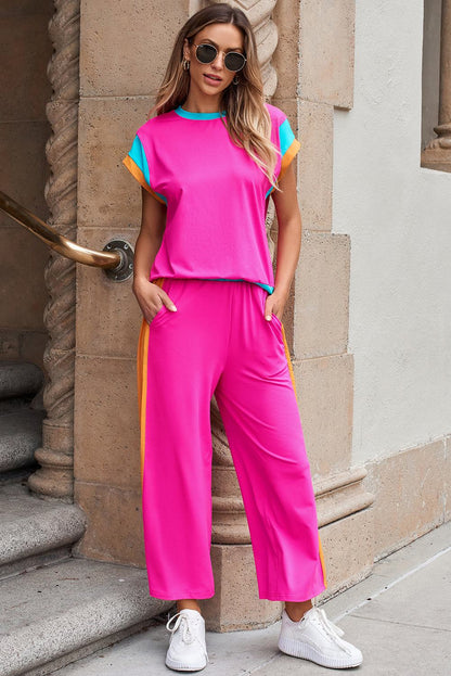 Woman wearing strawberry pink color block casual two-piece set with relaxed fit top and matching jogger pants, styled with white sneakers and sunglasses.