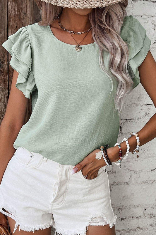 V-Neck Ruffled Cap Sleeve Blouse in light green with feminine ruffle details and cap sleeves, styled with white shorts.