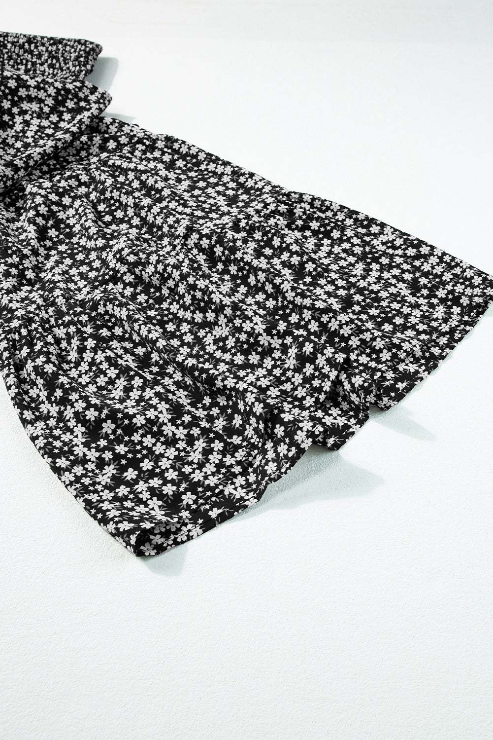 Black floral jumpsuit with wide leg design and smocked details on a white background.