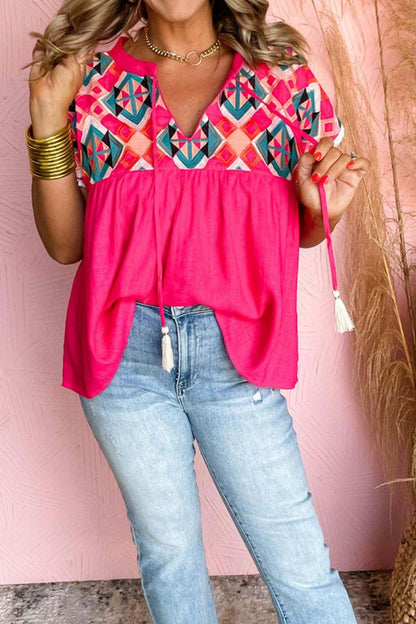 Bright colored summer blouse with embroidered tassel tie and geometric neck design.