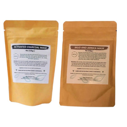 Two natural face mask products displayed side by side: left pouch contains Activated Charcoal Mask (4oz/113g) and right pouch contains Mud and Arnica Mask (4oz/113g), both in brown kraft paper stand-up pouches with white product labels