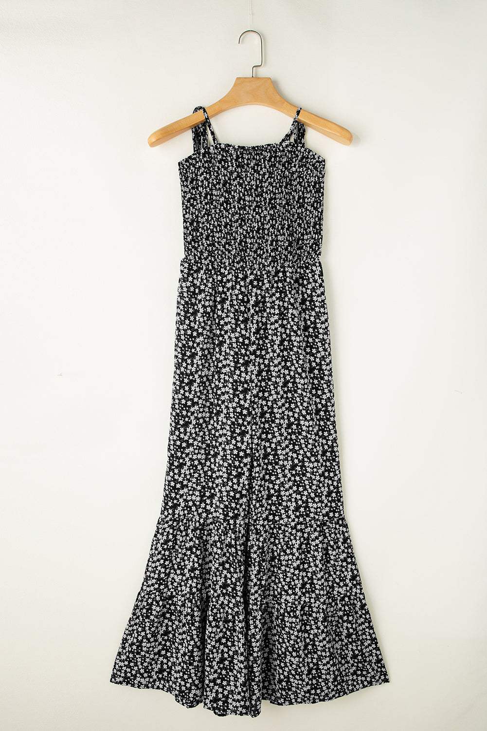 Black floral jumpsuit with thin straps, smocked bodice, and wide-leg design.