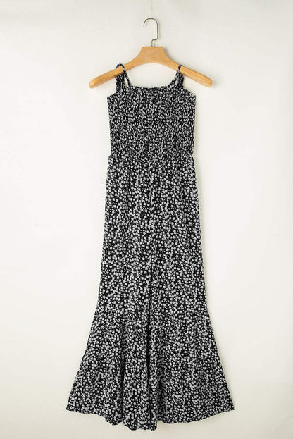 Black floral jumpsuit with thin straps, smocked bodice, and wide-leg design.