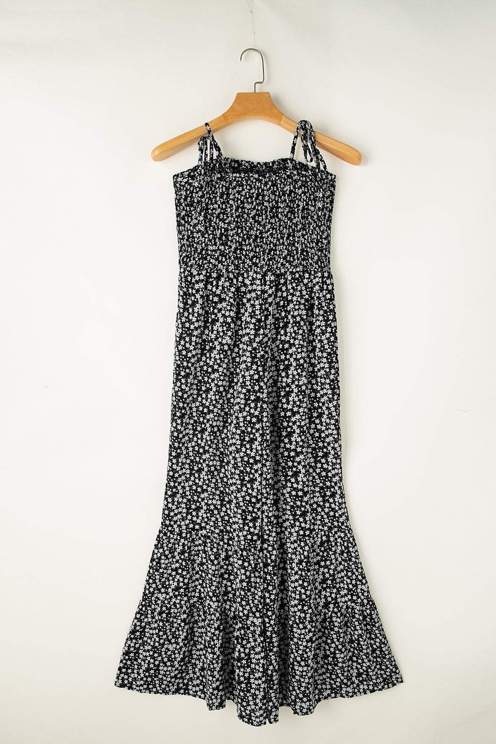Black floral jumpsuit with thin straps, smocked bodice, and wide-leg design.