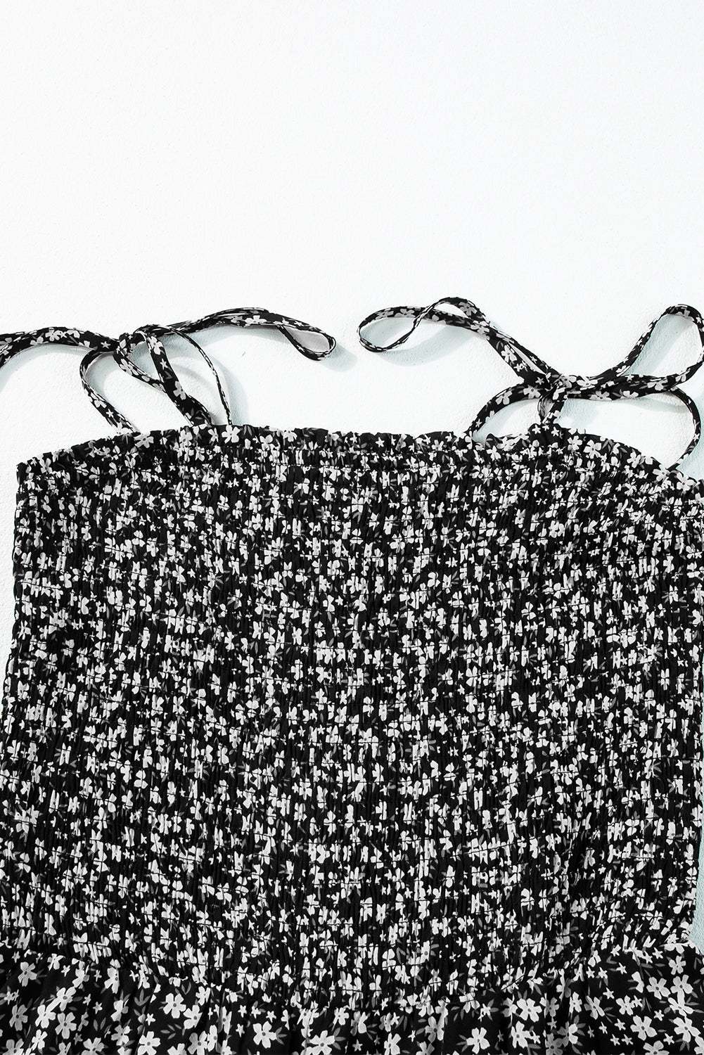 Black floral jumpsuit with thin straps and smocked bodice.